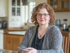 Vrouw aan de keukentafel kijken op haar mobiel